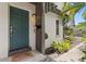 Inviting teal front door with a 'Stay awhile' welcome mat and lush tropical landscaping around the entrance at 441 75Th N Ave, St Petersburg, FL 33702