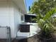 An exterior view of the house featuring a modern AC unit, privacy fence, screened lanai and palm trees at 4641 Carson Ne St, St Petersburg, FL 33703