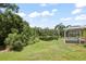 Expansive backyard view featuring a screened pool and a tranquil pond surrounded by lush greenery at 4948 Ridgemoor Cir, Palm Harbor, FL 34685
