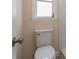 Bathroom features a white toilet, and a window with white trim at 5008 Glenn Dr, New Port Richey, FL 34652