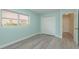 Minimalist bedroom features light blue walls, gray floors, window with views, and closet at 5008 Glenn Dr, New Port Richey, FL 34652