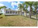 A view of the house's side and backyard, showcasing a large lawn and tropical palm trees at 5008 Glenn Dr, New Port Richey, FL 34652