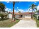 Single-story home with a red tile roof, well-kept lawn, and a circular driveway bordered by palm trees at 5008 Glenn Dr, New Port Richey, FL 34652