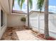 Enclosed brick patio featuring two palm trees and a hanging basket planter in an outdoor setting at 5008 Glenn Dr, New Port Richey, FL 34652
