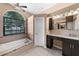 Bright bathroom features a tub under a large window and a vanity with dark cabinets at 5360 Karlsburg Pl, Palm Harbor, FL 34685