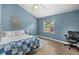 Comfortable bedroom with blue walls, wood floors, ceiling fan, and a window offering natural light at 5360 Karlsburg Pl, Palm Harbor, FL 34685