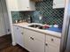 Kitchen sink area features white cabinetry, stainless steel sink, and unique tile backsplash at 5925 Terrace Park N Dr # 210, St Petersburg, FL 33709