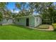 Charming backyard featuring a well-maintained lawn, lush trees, and a quaint, light green outbuilding at 8014 27Th N Ave, St Petersburg, FL 33710