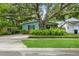 Charming home with turquoise exterior, lush garden, and a large shade tree in front at 8014 27Th N Ave, St Petersburg, FL 33710