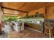 Covered outdoor kitchen featuring a stone bar, multiple barstools, cabinets, and a lush backyard view at 8105 N Grady Ave, Tampa, FL 33614
