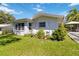 The side of a home with a well-manicured lawn and an open patio with seating, surrounded by lush landscaping at 917 Pineview Ave, Clearwater, FL 33756