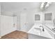 Bright bathroom featuring wood-look floors, white vanity and shower-tub combo at 10523 Boyette Creek Blvd, Riverview, FL 33569