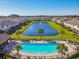 Aerial shot of a clear community pool and a pond, surrounded by palm trees and manicured green spaces at 11519 Crowned Sparrow Ln, Tampa, FL 33626