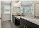 Bright bathroom featuring dual vanities with granite countertops, dark cabinets, and a glass-enclosed shower at 11519 Crowned Sparrow Ln, Tampa, FL 33626