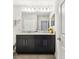 Bathroom with granite countertop, dual sinks, dark cabinetry, and modern fixtures; complemented with stylish decor at 11519 Crowned Sparrow Ln, Tampa, FL 33626