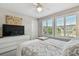 Bright bedroom featuring a TV, ceiling fan, and windows with views at 11519 Crowned Sparrow Ln, Tampa, FL 33626