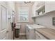 Functional laundry room with washer, dryer, storage cabinets, and a window for natural light at 11519 Crowned Sparrow Ln, Tampa, FL 33626