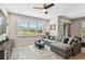 Bright living room with large sectional sofa, ceiling fan, and window with plantation shutters at 11519 Crowned Sparrow Ln, Tampa, FL 33626