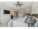 Cozy main bedroom featuring a ceiling fan, TV, and views of the main bath and walk-in closet at 11519 Crowned Sparrow Ln, Tampa, FL 33626