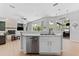 Open concept kitchen with stainless steel dishwasher, leading to living area with fireplace and backyard views at 12910 Vicksburg Dr, Tampa, FL 33625
