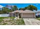 Single story home with neutral paint, arched windows, 2-car garage, and palm tree in the front yard at 13337 Tubeck St, Spring Hill, FL 34609