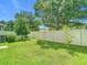 A spacious fenced backyard with lush green grass, healthy bushes, and a young sapling at 13806 Reindeer Cir, Hudson, FL 34669