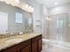 Bathroom showcasing double granite vanity, tiled floors and a glass-enclosed shower at 13806 Reindeer Cir, Hudson, FL 34669