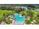 Community pool surrounded by lush landscaping, lounge chairs and umbrellas near pond at 13806 Reindeer Cir, Hudson, FL 34669