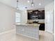 Well-lit kitchen featuring dark cabinetry, granite countertops, and a patterned island with a sink at 13806 Reindeer Cir, Hudson, FL 34669