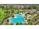 Aerial view of the large community pool with palm trees, lounge chairs, and a clubhouse at 13806 Reindeer Cir, Hudson, FL 34669