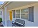Inviting front porch features updated windows, shutters, bench seating, and bright yellow front door at 1426 Gerard Ln, Holiday, FL 34690