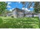 A large, green backyard featuring the home's exterior and screened-in pool area at 15206 Merlinpark Pl, Lithia, FL 33547
