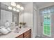 Cozy bathroom with a wood vanity, large mirror, and a door leading to the backyard at 15206 Merlinpark Pl, Lithia, FL 33547