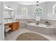 Bright bathroom featuring a soaking tub, a vanity, and tasteful decor, creating a spa-like atmosphere at 15206 Merlinpark Pl, Lithia, FL 33547