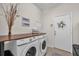 Modern laundry room with side by side washer and dryer and wood countertop at 15206 Merlinpark Pl, Lithia, FL 33547