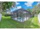 A screened-in pool view surrounded by well-manicured grass and lush landscaping at 15206 Merlinpark Pl, Lithia, FL 33547
