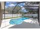 Backyard pool with a screened enclosure, surrounded by a white fence and lush greenery at 15206 Merlinpark Pl, Lithia, FL 33547