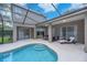 A screened-in pool and lounge area with sleek outdoor furniture and covered patio at 15206 Merlinpark Pl, Lithia, FL 33547