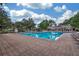 Large, rectangular swimming pool surrounded by brick pavers, seating, and lush landscaping at 15206 Merlinpark Pl, Lithia, FL 33547