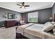Comfortable bedroom with dark walls, a ceiling fan, and a window overlooking the backyard at 1846 Moorhen Way, Lutz, FL 33558