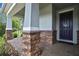 Charming front porch with stone pillar accents, a dark blue front door, and a welcome mat at 1846 Moorhen Way, Lutz, FL 33558