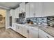 Kitchen with stainless steel appliances, granite countertops, and white cabinets, complemented by a mosaic backsplash at 1846 Moorhen Way, Lutz, FL 33558