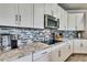 Kitchen featuring stainless steel appliances, granite counters, and white cabinets with sleek hardware and a backsplash at 1846 Moorhen Way, Lutz, FL 33558