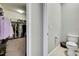 Walk-in closet featuring ample hanging storage and a glimpse into an adjacent toilet room at 1846 Moorhen Way, Lutz, FL 33558