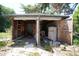 Exterior view of a dilapidated garage featuring exposed interior items and overgrown greenery surrounding it at 2355 Trelain S Dr, St Petersburg, FL 33712