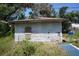 External view of a one story home detached garage structure, showing a weathered appearance, grass, and blue tarp at 2355 Trelain S Dr, St Petersburg, FL 33712