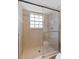 Bright bathroom shower featuring glass doors, neutral tile, and a window for natural light at 290 Winchester Way, Palm Harbor, FL 34684