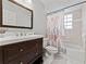 Updated bathroom with a wood vanity, large mirror, and a shower-tub combo with floral curtain at 290 Winchester Way, Palm Harbor, FL 34684