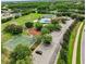 Wide aerial shot of the community amenities, including a playground, basketball court, and pool, surrounded by lush trees at 3718 Beneraid St, Land O Lakes, FL 34638