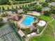 Aerial view of a community pool, tennis courts, playground, and beach volleyball surrounded by lush landscaping at 3718 Beneraid St, Land O Lakes, FL 34638